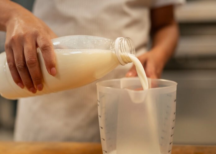 front view hand pouring milk cup