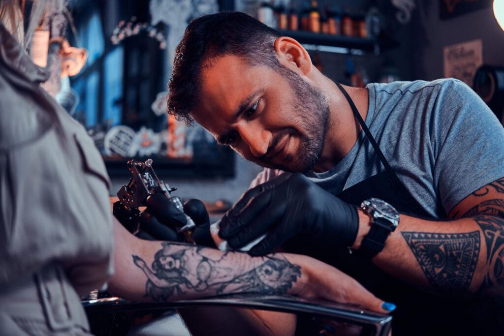 dilligent focused tattoo artist is creating new tattoo young woman s hand tatoo studio