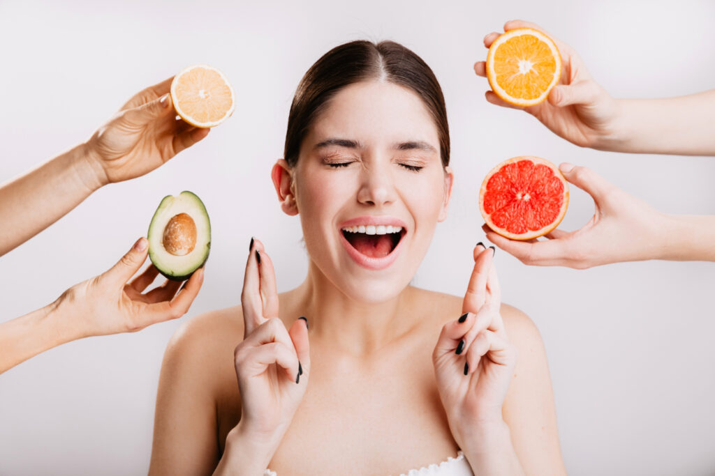 joyful girl makes wish portrait model without makeup white wall with fruits