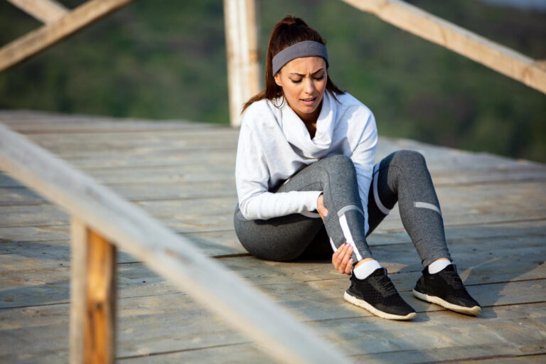 young sportswoman experiencing pain her leg while having sports training nature