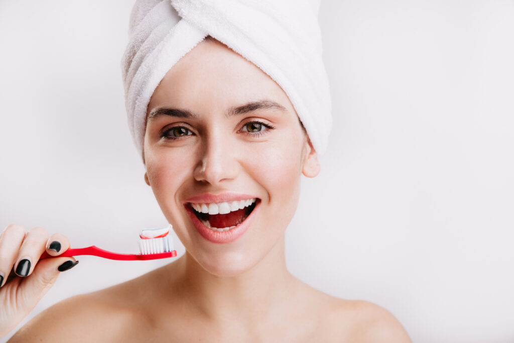 close up portrait contented girl with towel her head brunette with snow white smile is holding toothbrush