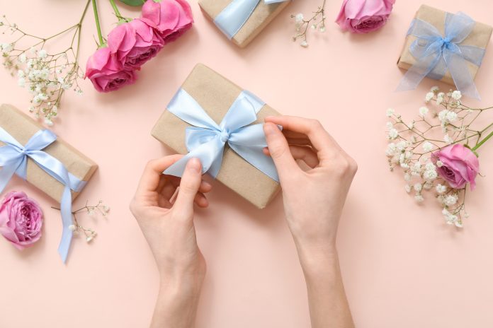 woman,wrapping,paper,gift,box,on,beige,background