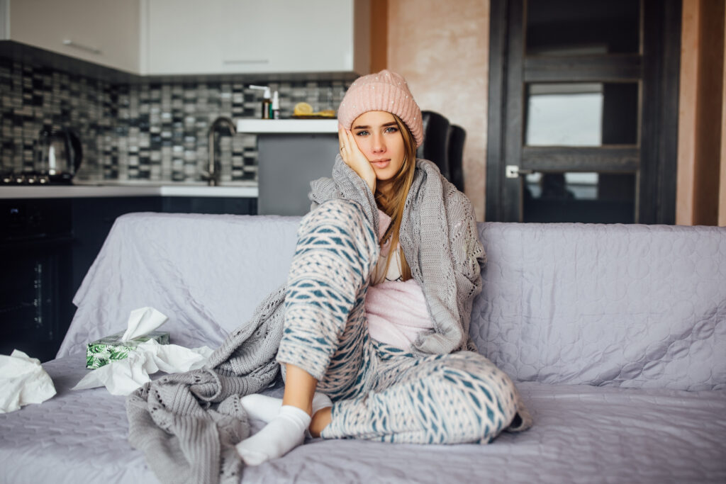 young beautiful sick girl resting on sofa under warm blanket at home.
